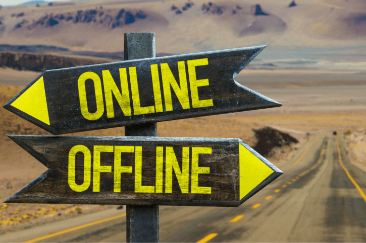 A closeup of a road sign with two arrows pointing in opposite directions. One is labeled, "Online," and the other is labeled, "OFFLINE."