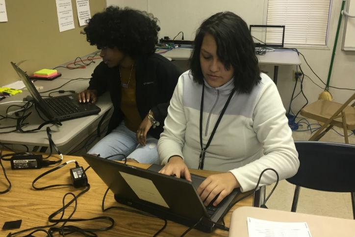 Two people working on laptops in a computer lab