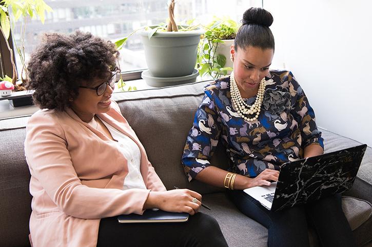 Two women with laptops sitting together