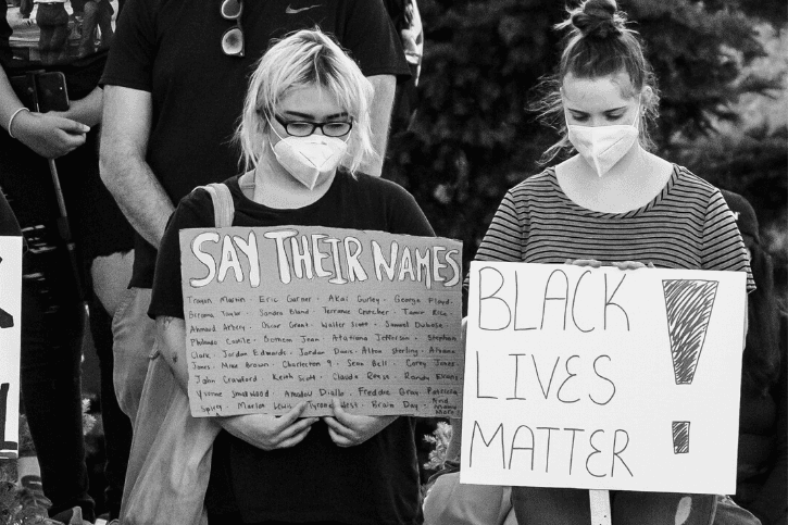 Women at a Peaceful vigil for George Floyd at the Lincoln Memorial. They hold signs reading, "SAY THEIR NAMES" and "BLACK LIVES MATTER!"