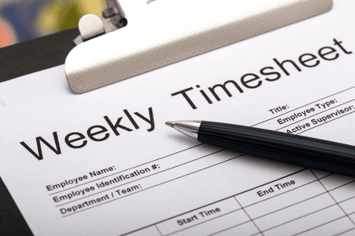 Close-up of a pen lying on a clipboard holding a weekly timesheet form