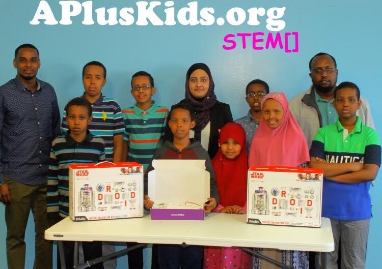 A group of students stand behind a folding table displaying their Star Wards Droid kits.