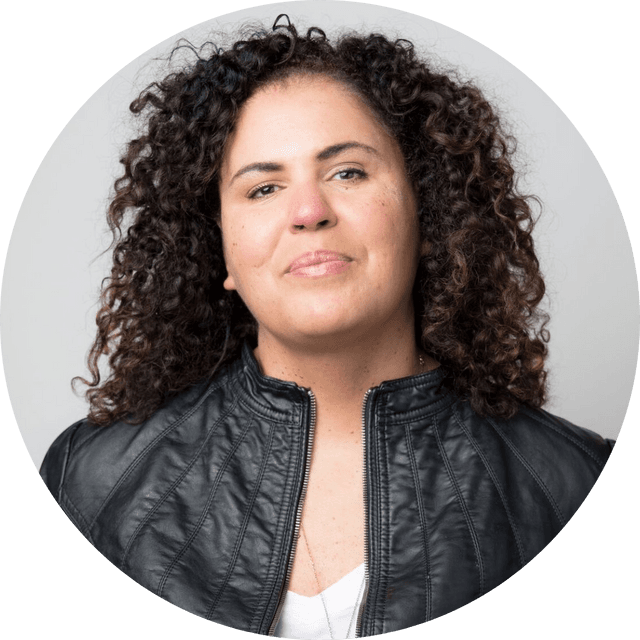 Headshot of Dr. Safiya Umoja Noble, looking at the camera, wearing a white top and black jacket, in front of a neutral background.
