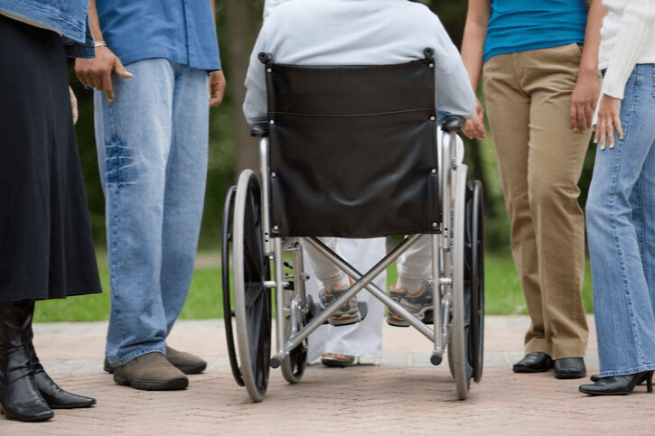 Several people standing outside with a person using a wheelchair