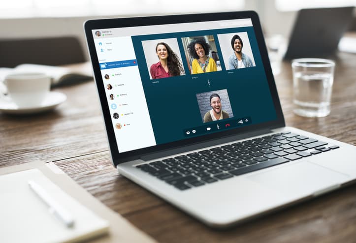 An open laptop showing a video call with four people.