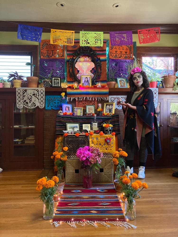 Maria wears skull Mexican makeup as she stands alongside the alter she created.