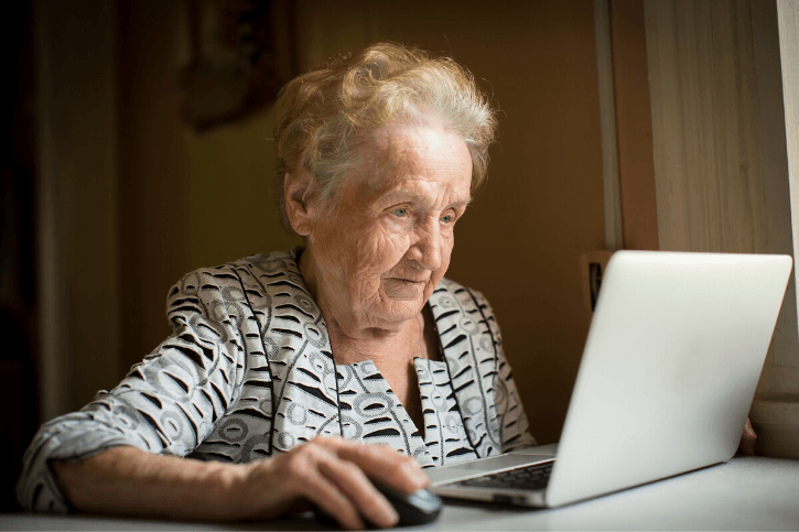 An older woman uses a mouse and a laptop