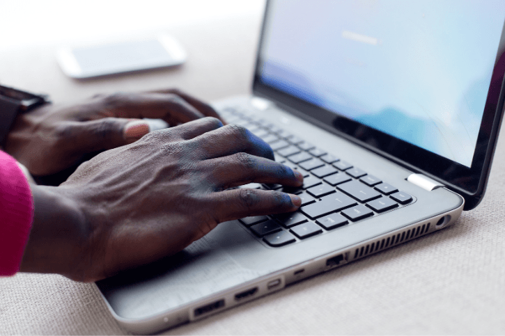 Closeup on a pair of hands resting on a laptop.